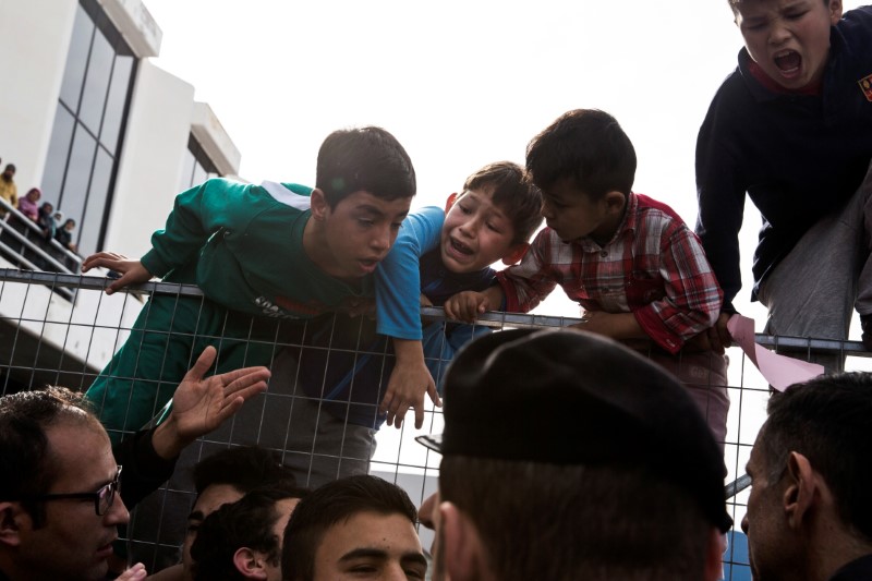 © Reuters. Crianças escalam entrada de um campo de refugiados, em Atenas