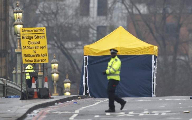 © Reuters. A police officer walks accross Westminster Bridge the morning after an attack by a man in a car and weilding a knife left five people dead and dozens injured, in London