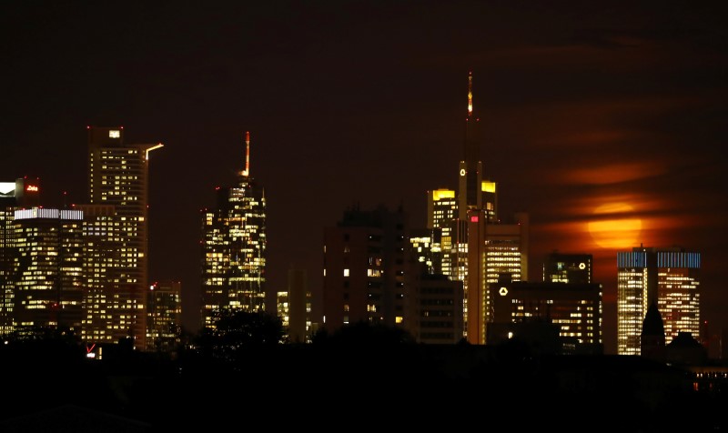 © Reuters. The moon is partly covered by clouds as it rises above the skyline of Frankfurt