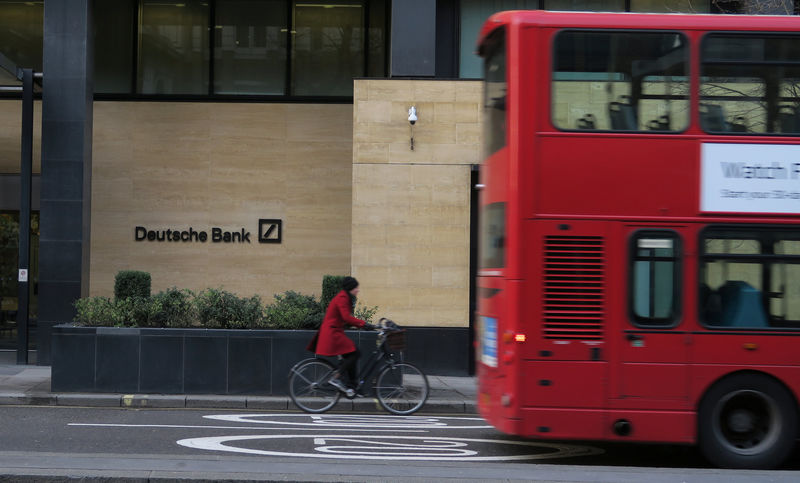© Reuters. FILE PHOTO: A woman cycles behind a London bus as they pass by a Deutsche Bank building in the City of London
