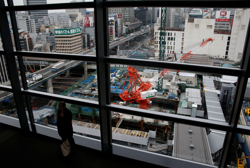 © Reuters. A man standing in front of windows with a view of a construction site in Tokyo