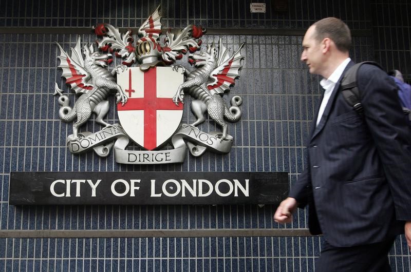 © Reuters. FILE PHOTO: Pedestrian walks past City of London emblem on Queen Victoria Street in central London.
