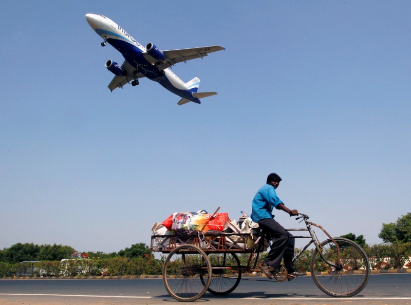 © Reuters. An IndiGo Airlines aircraft prepares to land as a man paddles his cycle rickshaw in Ahmedabad