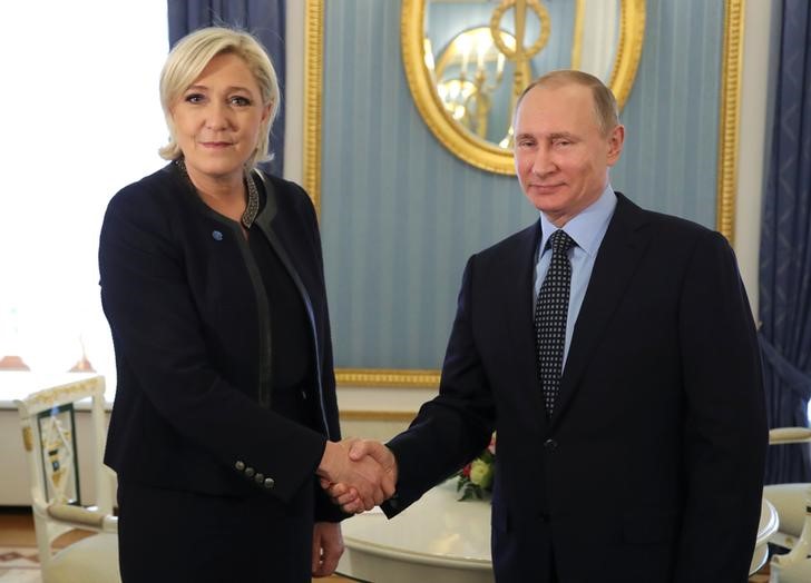 © Reuters. Russian President Putin shakes hands with French far-right party leader Le Pen during their meeting in Moscow