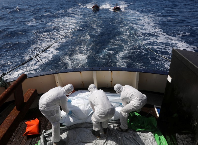 © Reuters. Rescuers sanitise dead bodies of migrants on board of a vessel in central Mediterranean Sea