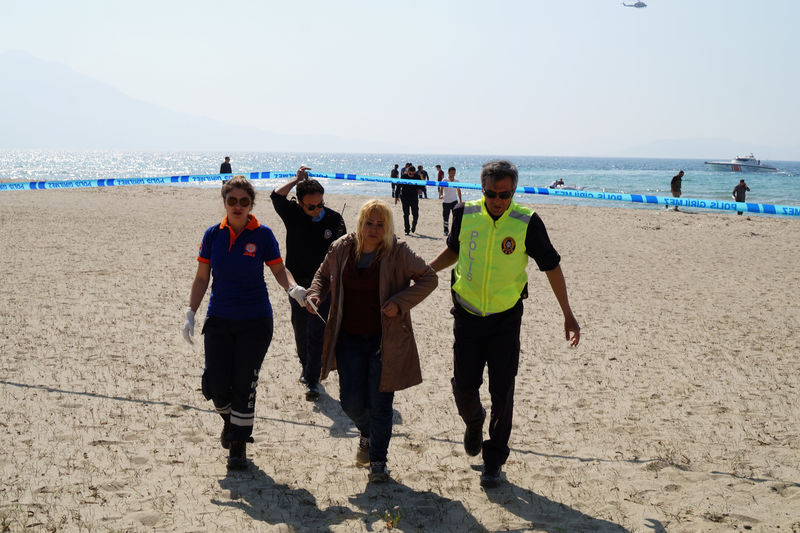 © Reuters. A woman, who survived after a plastic boat carrying Syrians to Greece sunk, is helped by a Turkish policeman and medics in the Aegean resort town of Kusadasi