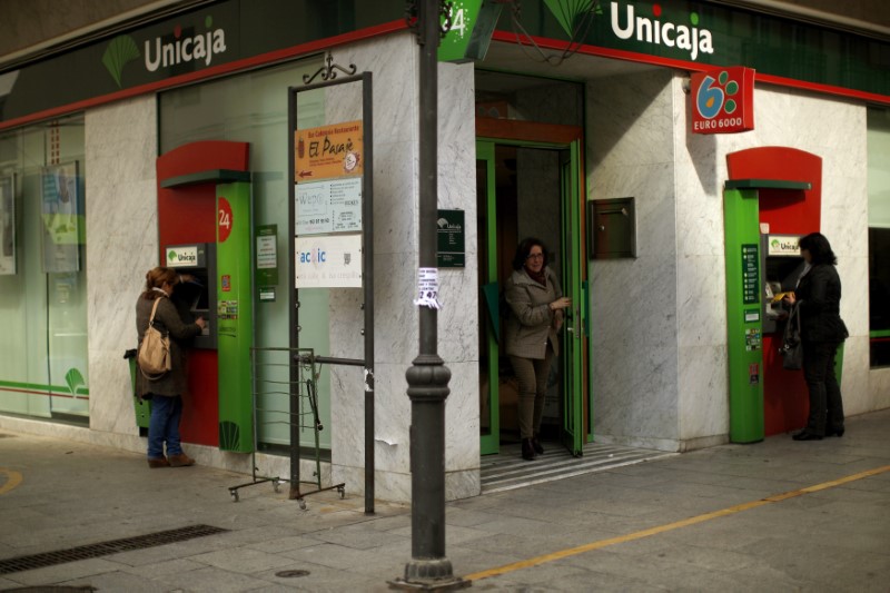 © Reuters. Women use ATM machines at a Unicaja bank branch at La Bola street in downtown Ronda