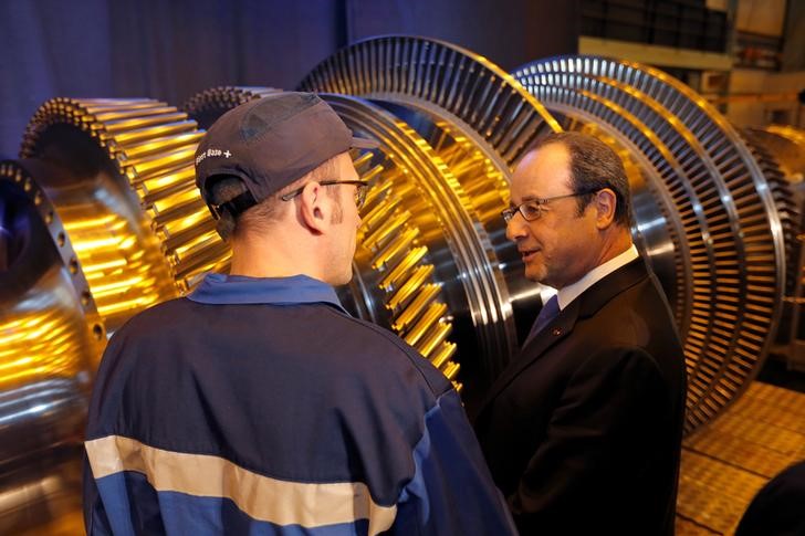 © Reuters. French President Hollande talks to a worker as he visits the turbines production unit of the General Electric plant in Belfort