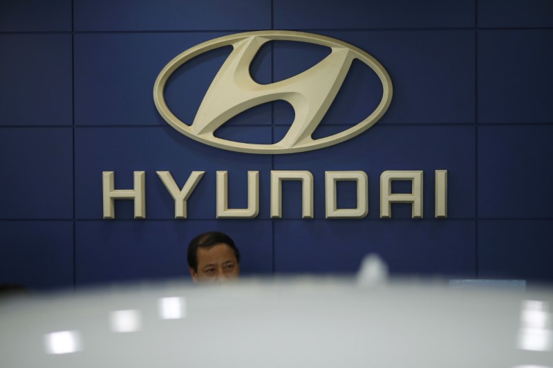 © Reuters. An employee sits in front of the logo of Hyundai Motor Co. at its dealership in Seoul