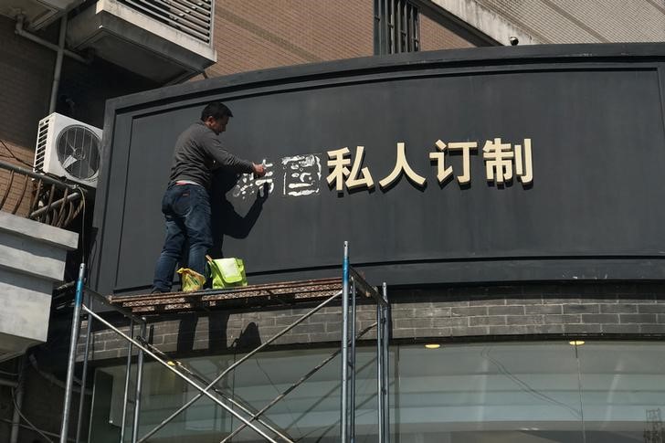 © Reuters. A worker removes part of a sign that consists of the Chinese characters that collectively read South Korea, at a shop in Shanghai,