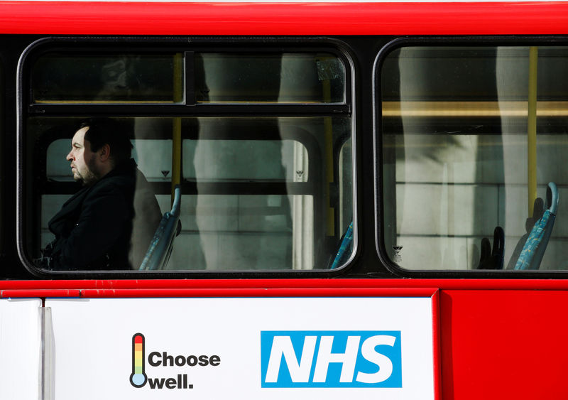 © Reuters. FILE PHOTO:  A man sits on a bus with an advertisement for Britain's National Health Service (NHS) in London
