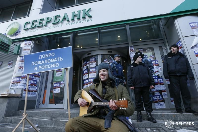 © Reuters. Member of Azov civil corp attends protest in front of branch of Sberbank, which protesters say supports Russian "aggression" in Eastern Ukraine, in Kiev