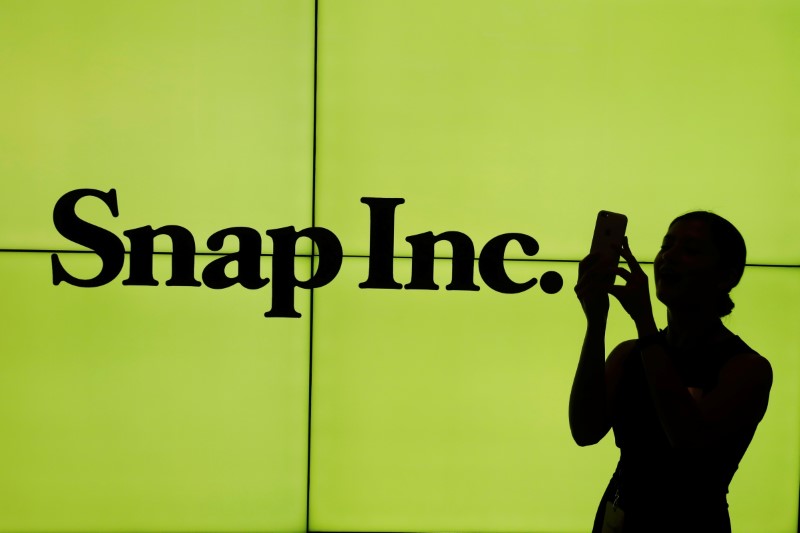 © Reuters. A woman stands in front of the logo of Snap Inc. on the floor of the New York Stock Exchange (NYSE) while waiting for Snap Inc. to post their IPO, in New York City