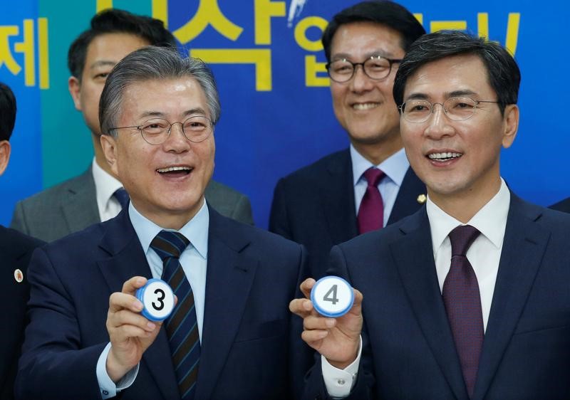 © Reuters. The Democratic Party's candidates for the presidential primary Moon Jae-in and Ahn Hee-jung pose with their elective symbol numbers at an event to declare their fair contest in the party's presidential primary in Seoul