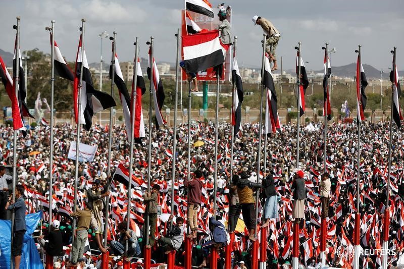 © Reuters. Supporters of the Houthi movement and Yemen's former president Ali Abdullah Saleh climb flag poles as they attend a joint rally to mark two years of the military intervention by the Saudi-led coalition, in Sanaa, Yemen