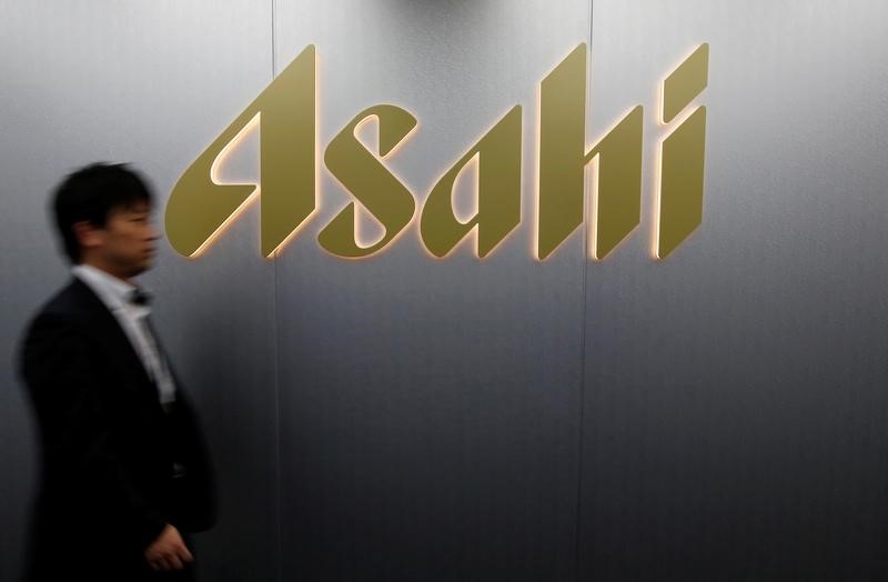 © Reuters. Man walks past the logo of Asahi Group Holdings at the company's headquarters in Tokyo