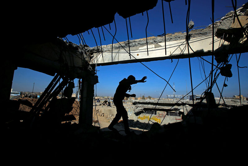 © Reuters. An Iraqi runs through a destroyed building as Iraqi forces battle with Islamic State militants, in western Mosul