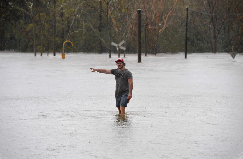 © Reuters. A local resident wades into flood waters blocking the road between the townships of Airlie Beach and Proserpine after Cyclone Debbie hit the area in northern Queensland, located south of Townsville in Australia