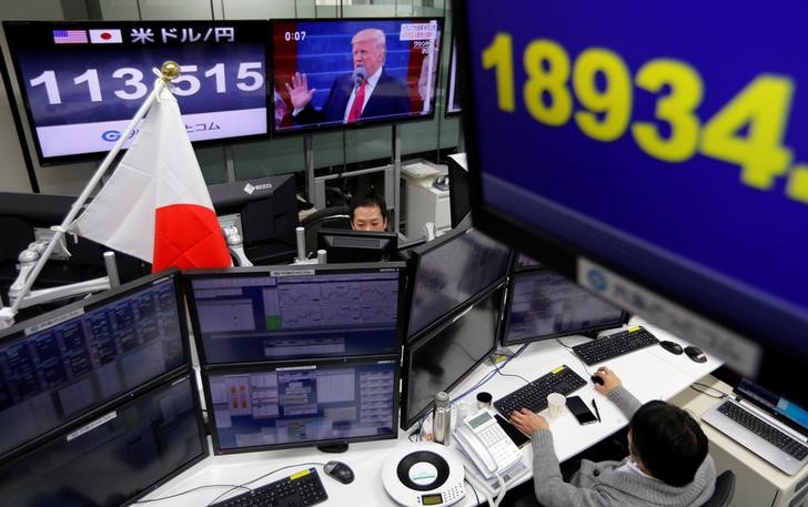© Reuters. Employees of a foreign exchange trading company work near monitors showing U.S. President Trump, the Japanese yen's exchange rate against the U.S. dollar and Japan's Nikkei share average in Tokyo