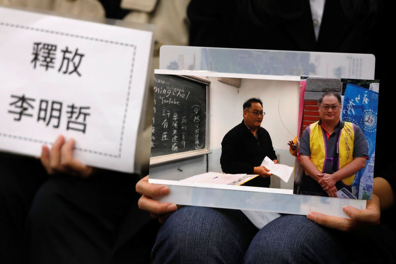 © Reuters. Li Ching-yu, wife of Taiwanese human right activist Li Ming-che, detained in China, holds photos of her husband at a news conference in Taipei,
