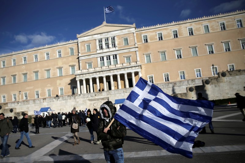 © Reuters. FILE PHOTO:A farmer waves a Greek national flag in front of the parliament building during a demonstration to demand tax reductions and compensation, in Athens
