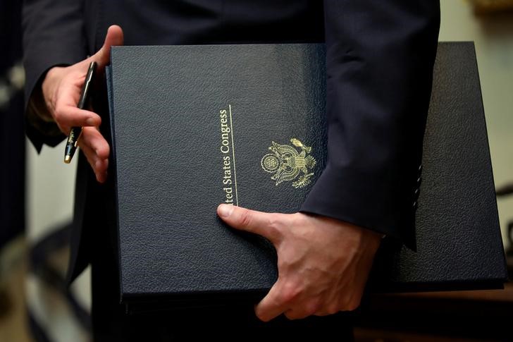 © Reuters. A White House aide holds four new bills to be signed by U.S. President Donald Trump during a bill signing event in the Roosevelt room of the White House in Washington