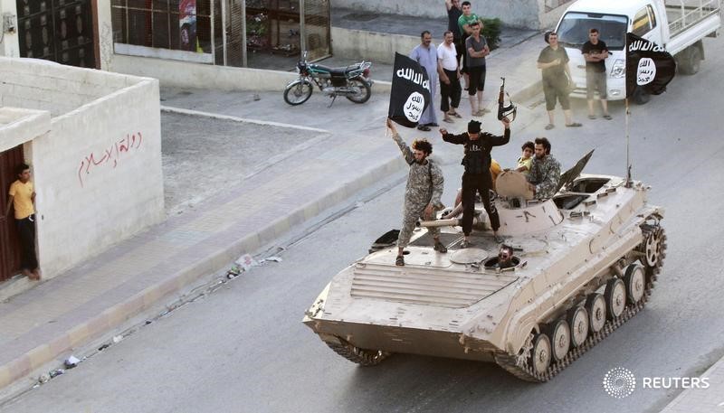 © Reuters. Исламисты с флагом "Исламского государства" в Ракке