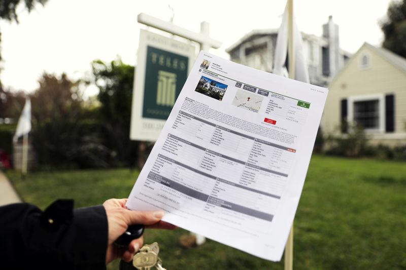 © Reuters. FILE PHOTO --  A woman holds a piece of paper advertising a home for sale in Santa Monica