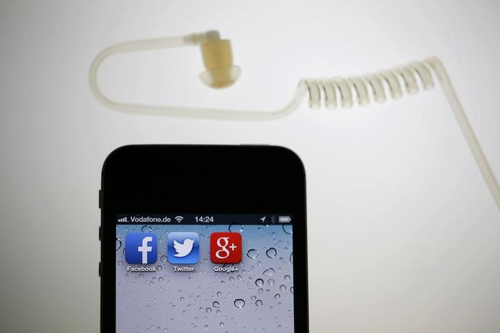 © Reuters. Illustration picture of application icons of Facebook Twitter and Google on iPhone next to earphone set in Berlin
