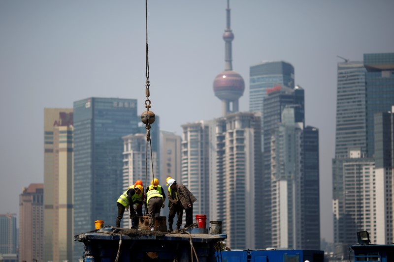 © Reuters. Workers work at a construction site in front of Shanghai's financial district of Pudong in Shanghai