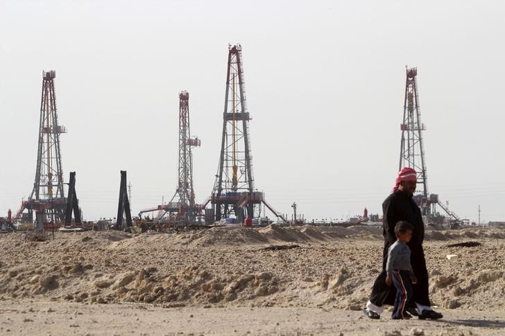 © Reuters. Мужчина с ребенком у нефтяного месторождения Румайла в Басре