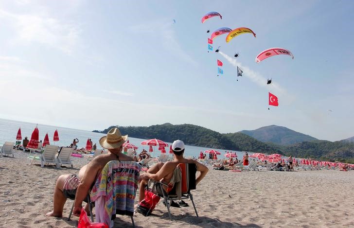 © Reuters. Local and foreign tourists watch International Oludeniz Air Games as they enjoy the sunny weather on a beach in Fethiye in Mugla province