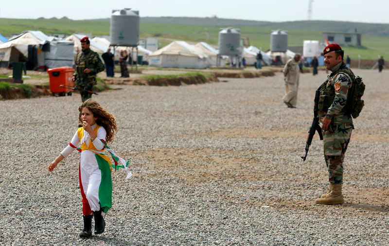 © Reuters. A girl walks by as a security guard is on patrol during the visit of UN Secretary General Guterres at Hasansham camp, in Khazer