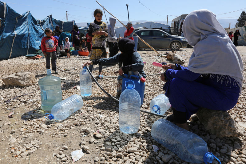 © Reuters. Syrian refugees fill bottles of water at a makeshift settlement in Bar Elias town, in the Bekaa valley