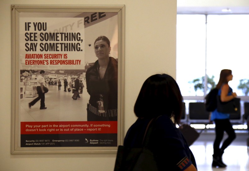 © Reuters. A poster regarding airport security hangs from a wall as passengers walk around the departures area at Sydney International Airport, Australia