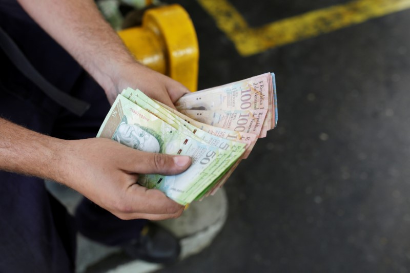 © Reuters. A worker counts Venezuelan bolivar notes at a gas station of Venezuelan state oil company PDVSA in Caracas