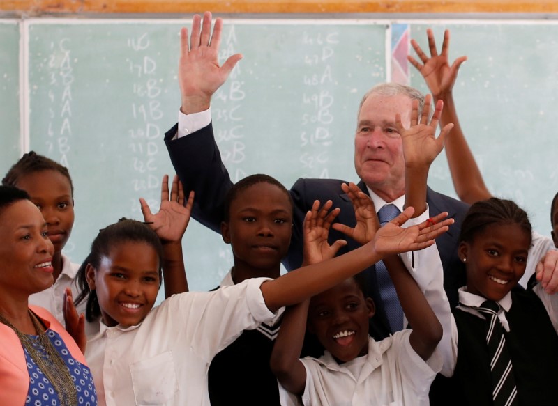 © Reuters. Former US President George W. Bush poses for a photograph with children at a school in Gaborone