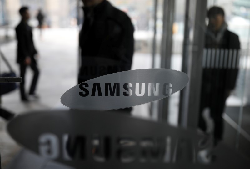 © Reuters. Shareholders walk past the logo of Samsung Electronics before their general meeting at a company's building in Seoul