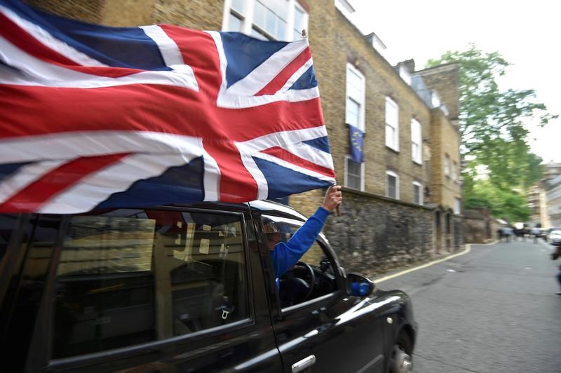 © Reuters. A taxi driver holds a Union flag, as he celebrates following the result of the EU referendum, in central London