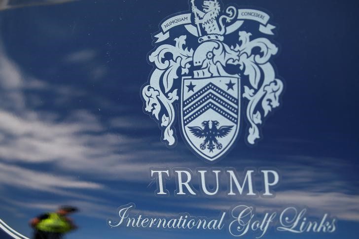 © Reuters. A police officer is reflected in a golf cart as people wait for Republican presidential candidate Donald Trump to land on the golf course at his Trump International Golf Links in Aberdeen