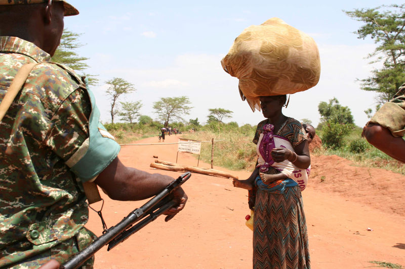 © Reuters. A South Sudanese refugee woman carries her child and belongings as she talks to a Uganda People's Defence Forces soldier after crossing into Uganda at the Ngomoromo border post in Lamwo district, northern Uganda