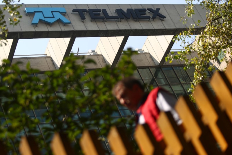 © Reuters. A man crosses a pedestrian bridge next to the headquarters of internet and fixed-line phone company Telmex, commercial brand of America Movil, in Mexico City