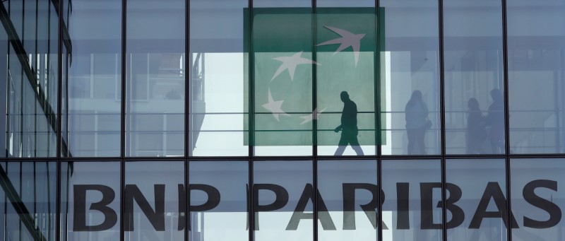 © Reuters. A man is seen in silhouette as he walks behind the logo of BNP Paribas in a building in Issy-les-Moulineaux, near Paris