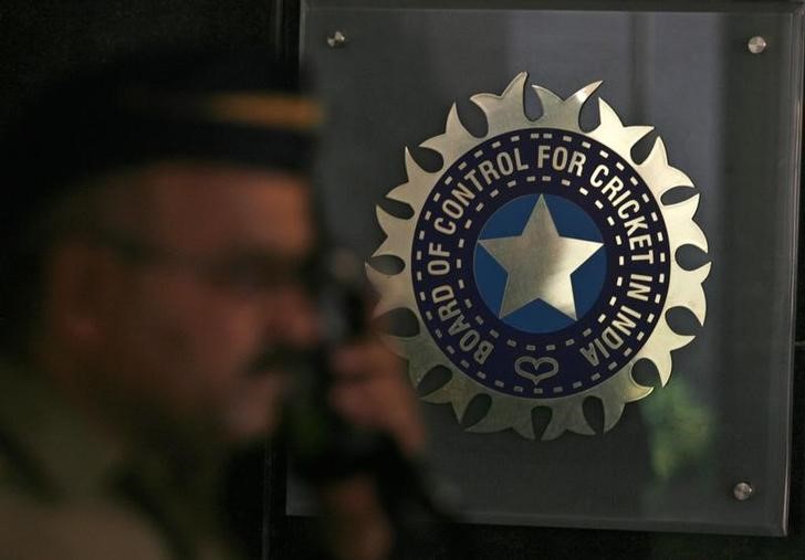 © Reuters. A policeman walks past logo of BCCI in Mumbai