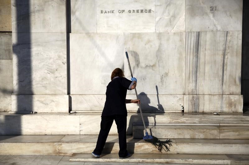 © Reuters. A cleaning lady mops the steps at the main entrance of the Bank of Greece headquarters in Athens