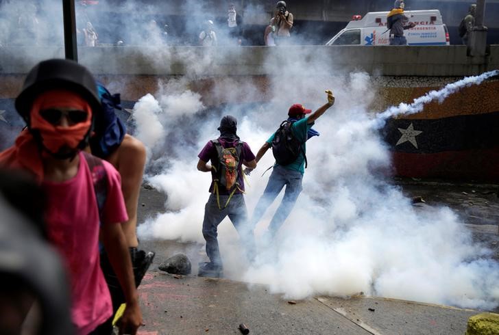 © Reuters. Manifestantes em meio a gás disparado pela polícia em Caracas