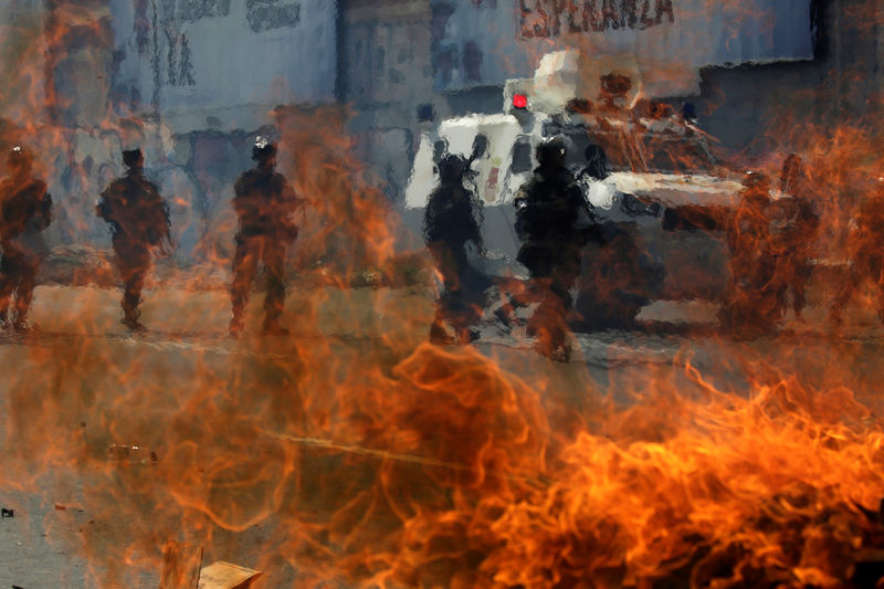 © Reuters. Guarda nacional da Venezuela passa por um bloqueio em chamas durante confrontos com manifestantes em protestos em Caracas.