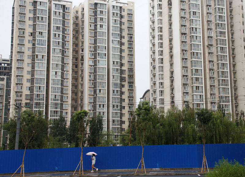© Reuters. FILE PHOTO: A woman walks past residential buildings in Beijing