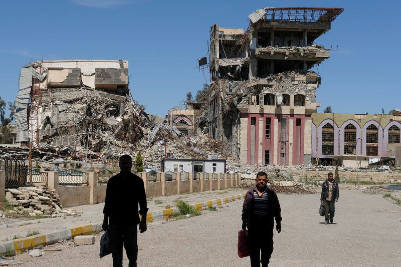 © Reuters. People walk in front of remains of University of Mosul in Mosul