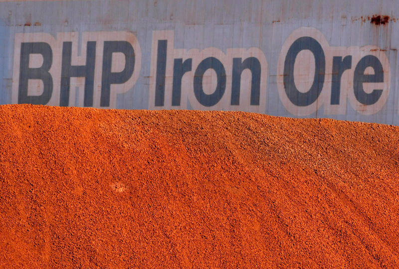 © Reuters. FILE PHOTO:  A BHP Billiton sign is visible behind a pile of iron ore at the company's loading facility in Port Hedland